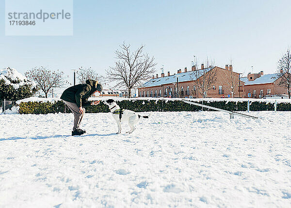 Mann trainiert seinen Hund im Schnee