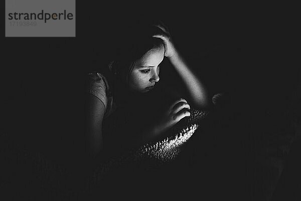 Mädchen benutzt ein Tablet in einem dunklen Raum