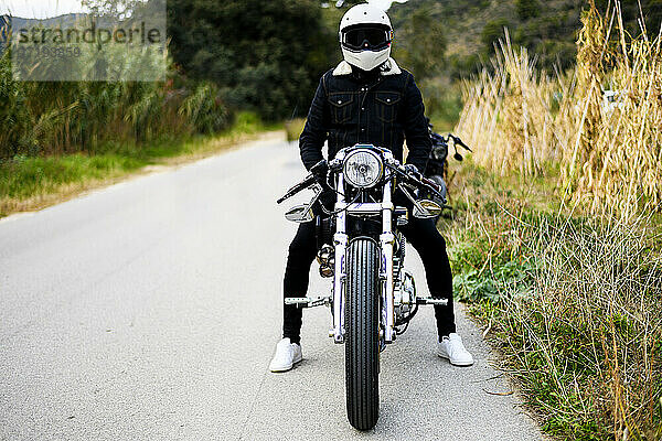 Vorderansicht eines Motorrads  das mit seinem Besitzer allein auf der Straße steht