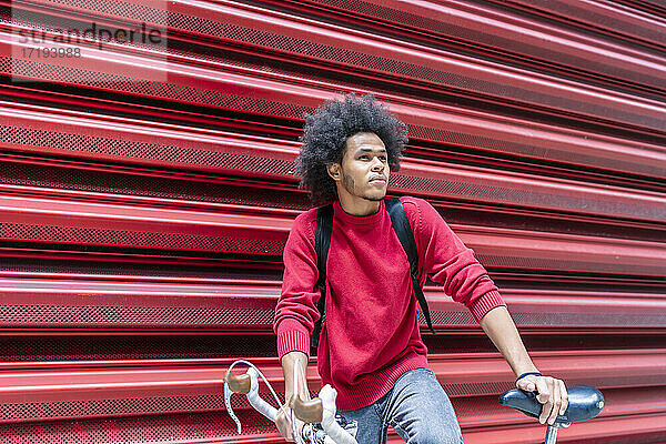 junger Mann mit Afrofrisur mit seinem Fahrrad