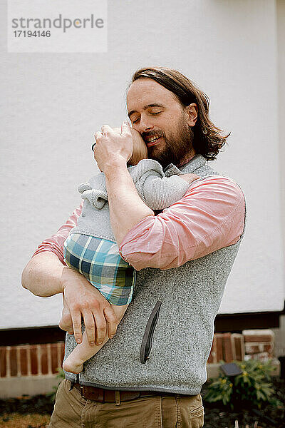 Süßer Vater umarmt Kleinkind Sohn in Pastellfarben draußen im Frühling