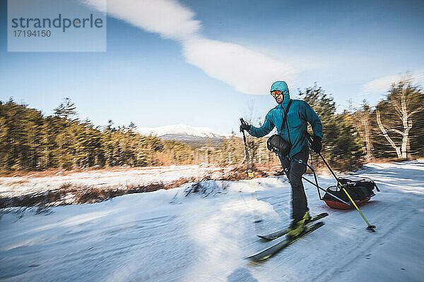 Mann fährt auf einer verschneiten Piste Ski und zieht einen Schlitten  Katahdin  Maine