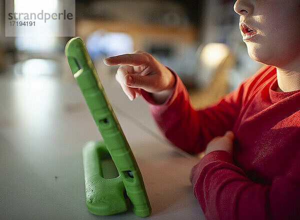 Nahaufnahme eines Kindes  das auf ein elektronisches Tablet zu Hause zeigt