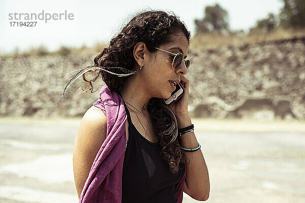 Mexikanische junge trendige Frau am Telefon in trockener Natur