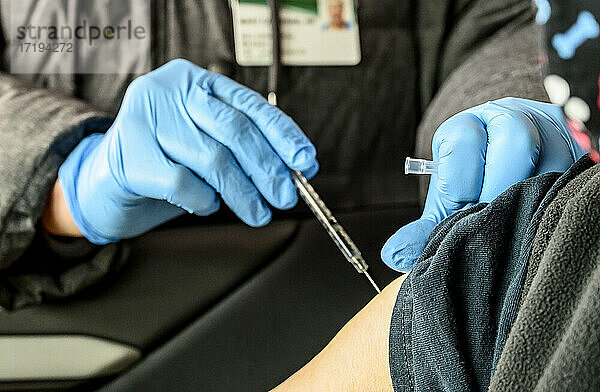 Eine Krankenschwester injiziert die Covid-19-Impfung in den Arm einer Frau in einer Drive-Thru-Ausgabestelle.