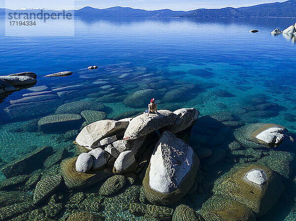 junge frau sitzt auf felsen im lake tahoe an einem sonnigen nachmittag