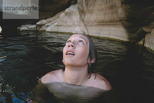 Junge mit nassen Wimpern blickt aus einem Schwimmloch nach oben