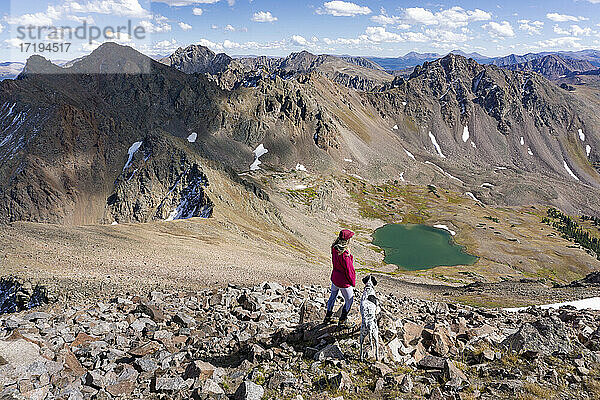 Frau beim Wandern mit Hund auf einem Berg im Urlaub