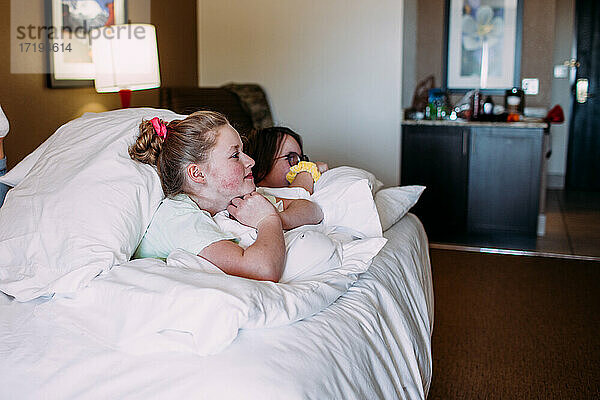 Zwei glückliche junge Mädchen entspannen sich auf einem Bett in einem Hotelzimmer