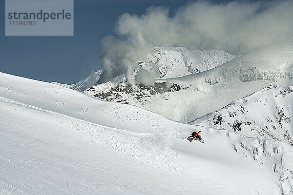 Mann Snowboarding auf schneebedeckten Berg gegen Himmel im Urlaub