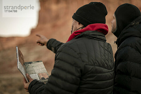 Männliche Freunde diskutieren über eine Karte  während sie den Canyonlands National Park erkunden