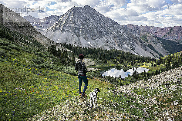 Wanderin mit Hund schaut auf einen schönen Berg