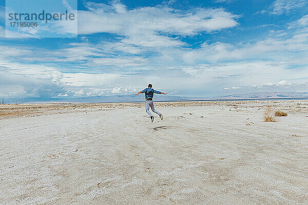 Person springt am Strand - Konzept der Levitation. Windiger Tag