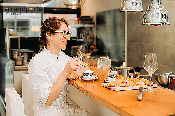 Köchin in Uniform macht Kaffeepause an der Theke eines Restaurants