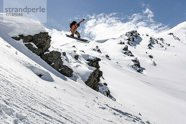 Mann beim Snowboarden auf einem schneebedeckten Berg im Urlaub