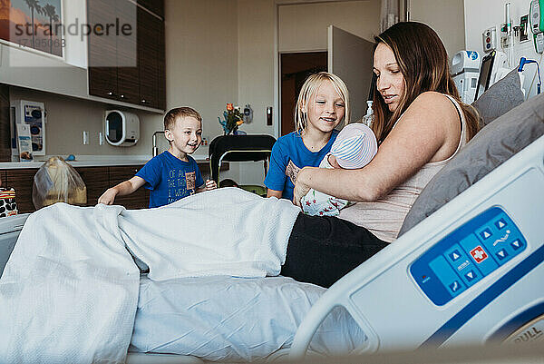Junge Brüder treffen ihr neugeborenes Baby zum ersten Mal im Krankenhaus