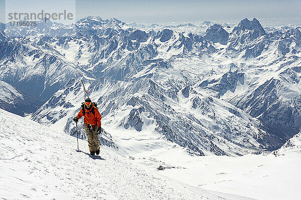 Mann mit Skistock beim Besteigen eines schneebedeckten Berges im Urlaub