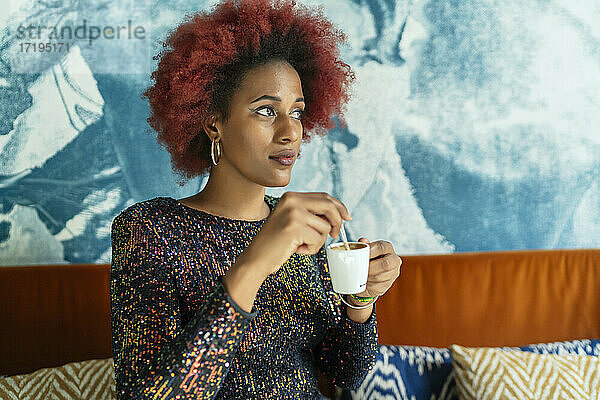 schöne Frau mit Afro-Haar trinkt einen Kaffee