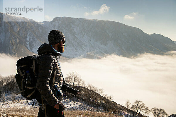Porträt eines gut aussehenden Mannes beim Trekking in den Bergen im Winter draußen