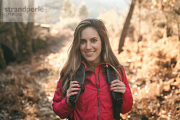 Nahaufnahme eines hübschen und abenteuerlustigen Mädchens  das auf einer Reise im Wald lächelt.