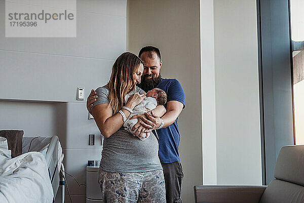 Neugeborener Junge wird von neuen Eltern im Geburtshaus in den Arm genommen