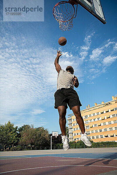 Afroamerikanischer Spieler  der unter den Basketballkorb springt