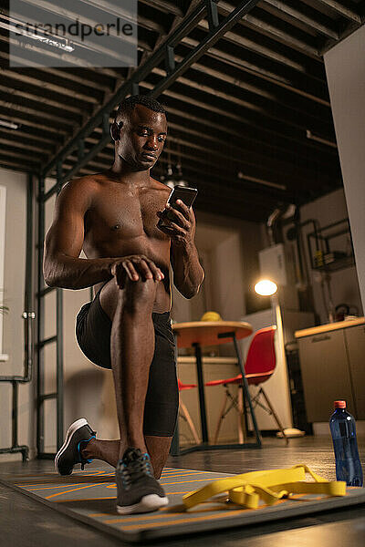 Afroamerikanischer Sportler mit Smartphone und Longieren