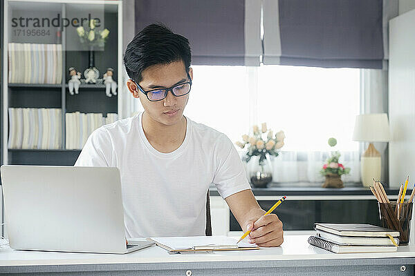 Junger Mann arbeitet und lernt online zu Hause.