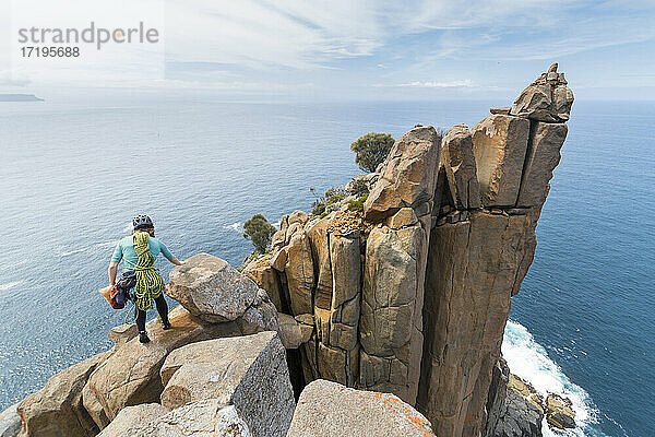 Eine Abenteurerin macht sich auf den Weg ins Unbekannte  bewaffnet mit Seilen und Kletterausrüstung  um Doleritfelsen in den Meeresklippen von Cape Raoul in Tasmanien  Australien  zu erkunden.