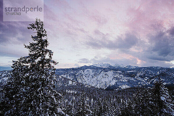 Sonnenuntergang über schneebedeckten Bergen mit blauen und violetten Farbtönen