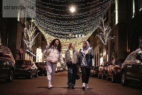 Weibliche Freunde unterhalten sich auf der Straße in der Stadt bei Nacht im Winter