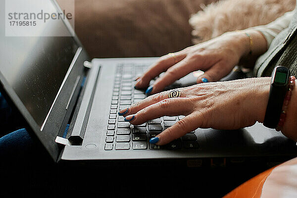 Nahaufnahme einer Frau mittleren Alters  die aus der Ferne mit ihrem Laptop arbeitet