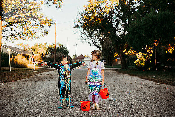 Junge Kinder stehen in der Straße gekleidet für Halloween bei Sonnenuntergang