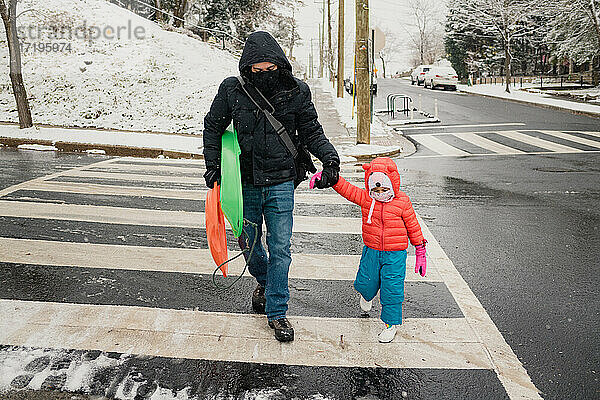 Vater und Kind beim Überqueren der Straße im Schneesturm