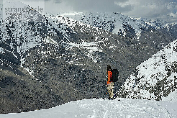 Mann mit Splitboard und Blick auf den Berg  während er im Urlaub auf einem Schneefeld steht