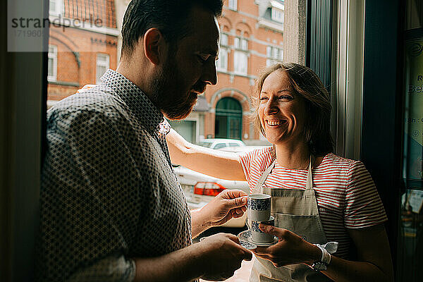 Ein Ehepaar steht am Eingang mit einer Tasse Kaffee  lächelnd