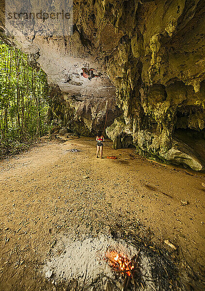 junger Mann beim Klettern an einer überhängenden Felswand im Wald am Strand von Railay