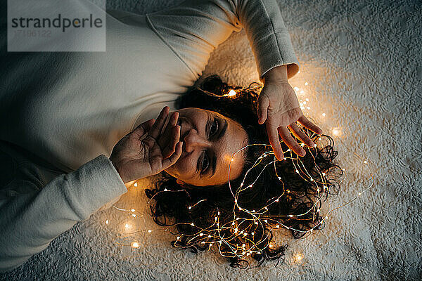 Liegende Frau mit verhedderter Lichterkette im Haar  lächelnd