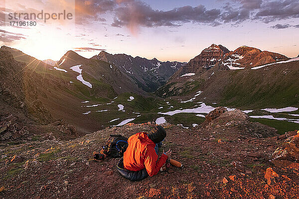 Weibliche Wanderin sitzt auf einem Berg gegen den Himmel bei Sonnenuntergang