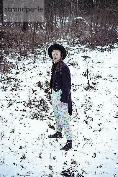 Androgyne gemischtrassige Frau steht mit schwarzer Smokingjacke im Schnee