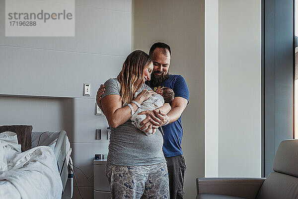 Neugeborener Junge wird von neuen Eltern im Geburtshaus in den Arm genommen