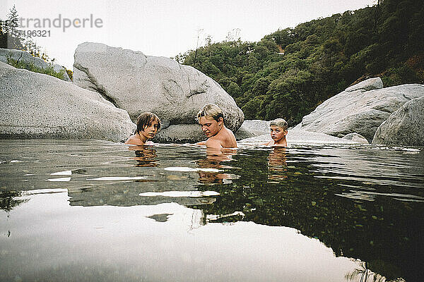 Drei Jungen entspannen sich in einem Wasserbecken in der Abenddämmerung
