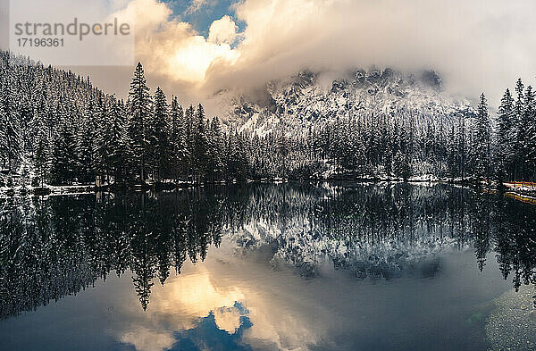 Dramatische Landschaft eines Sees im Wald in der Nähe von Bergen im Winter.