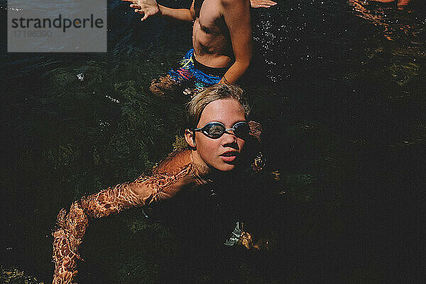 Junge mit Schwimmbrille schaut von einem kalifornischen Schwimmloch auf.