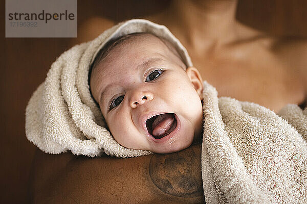 Ein wunderschönes Baby in ein Handtuch gewickelt  das den Mund mit seiner Mutter öffnet