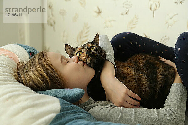 Kind küsst eine Katze. Mädchen und Katze in Großaufnahme.