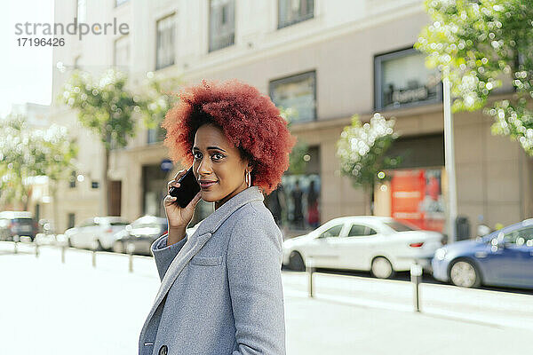 schöne Frau mit Afro-Haar  die mit ihrem Smartphone spricht