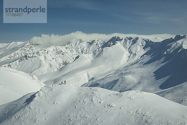 Menschen Snowboarden auf schneebedeckten Berg gegen Himmel
