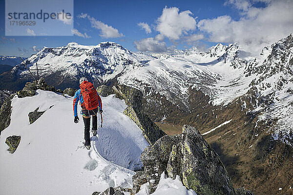 Ein Mann besteigt an einem sonnigen Tag einen verschneiten Berg in Devero  Italien.