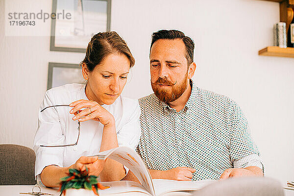 Mann und Frau lesen zusammen ein Buch mit ernstem Gesichtsausdruck